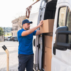 Delivery driver organizing packages in a delivery van. Delivery driver concept in a van. Man in blue uniform arranging boxes inside a delivery vehicle, representing logistics and shipping.